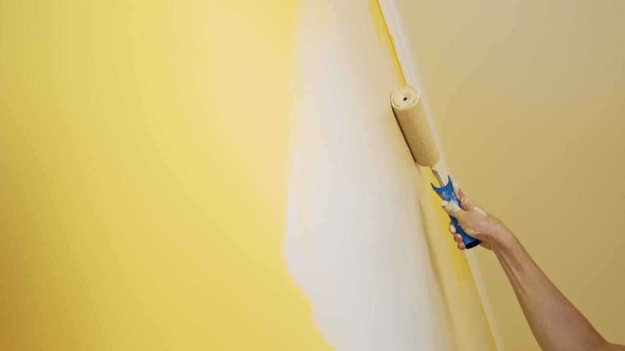 Man painting wall in room. Close up of man in new apartment renovating room painting wall with brush roller