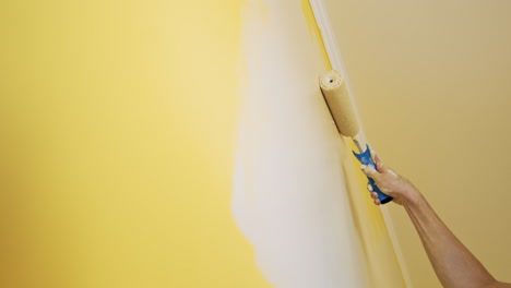 man painting wall in room. close up of man in new apartment renovating room painting wall with brush roller