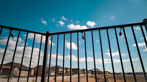 Lapso-De-Tiempo-Panorámico-Del-Paisaje-Nuboso-Desde-La-Cubierta-De-Una-Casa-Suburbana-Vista-A-Través-De-La-Barandilla-De-La-Cubierta