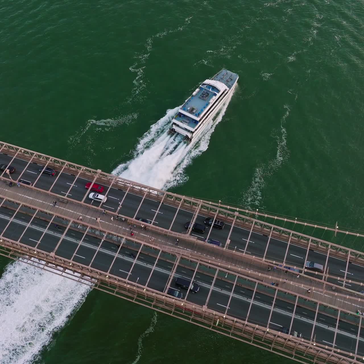 Big city bridge with transport traffic roads and pedestrian zone. White yacht sailing under the bridge. Top view