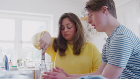 Una-Pareja-Joven-Con-Síndrome-De-Down-Batiendo-Huevos-Para-Una-Receta-De-Pastel-Que-Están-Horneando-En-La-Cocina-De-Casa