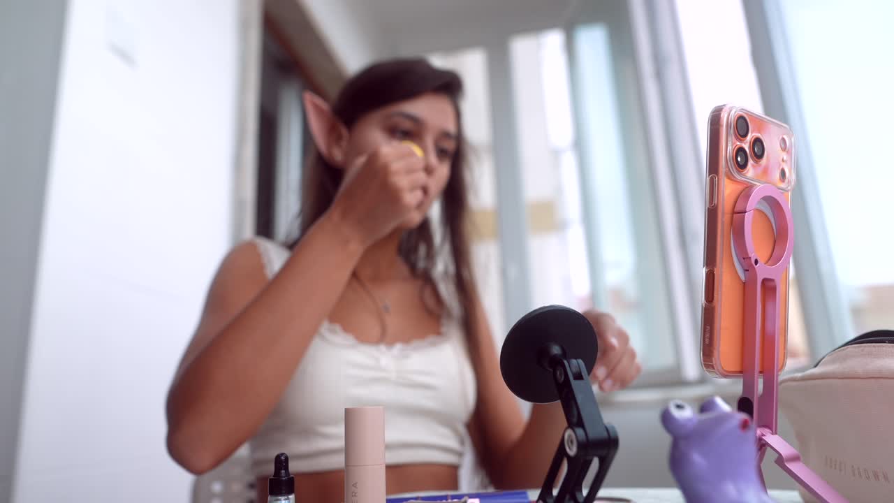 Giovane donna con orecchie da elfo che applica trucco per un tutorial di bellezza