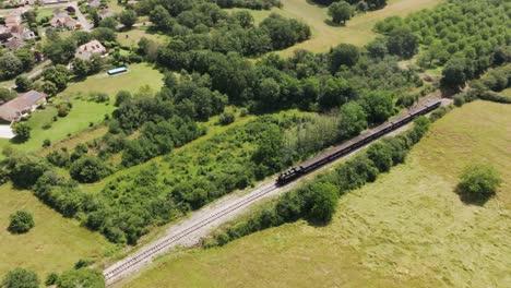 Wide-shot-of-a-steam-locomotive-in-the-countryside,-like-a-western,-smoke-coming-out-of-the-chimney,-Lot,-France