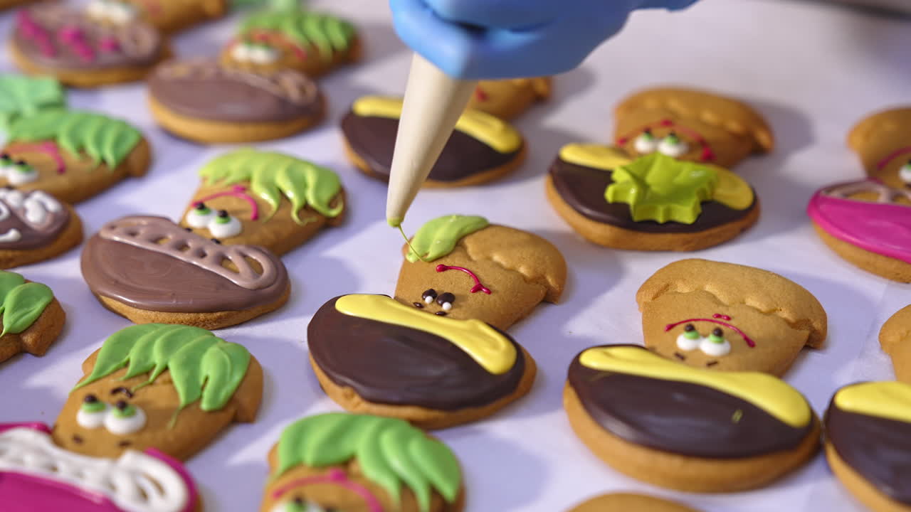 Cookies production in confectionary factory. Hands in gloves decorate biscuits in the shape of mushrooms with creamy decorations. Close up.