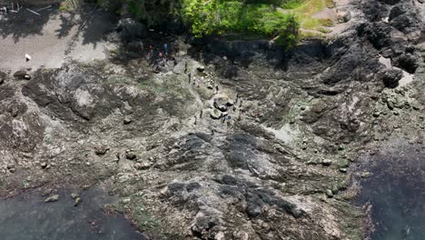 Orbiting-aerial-shot-of-people-exploring-in-the-Rosario-Beach-tidal-pools-in-WA-State