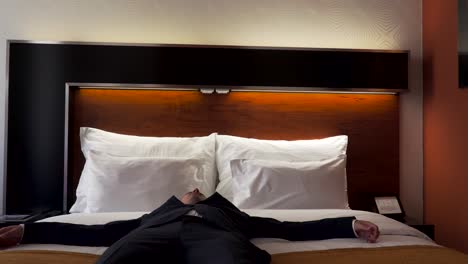 tired male business traveler falling into hotel room bed