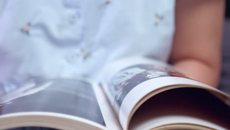 un primer plano de una persona hojeando las páginas de un libro ilustrado mientras lee