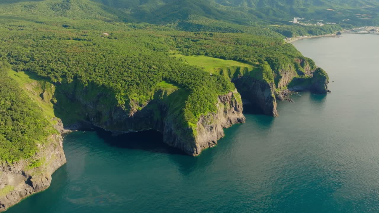 Aerial fly above waters and green rocky coast in Shiretoko Peninsula, Hokkaido, Unesco National Park