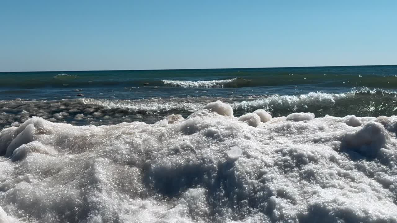 olas rompiendo en un pedazo gigante de hielo en el lago michigan