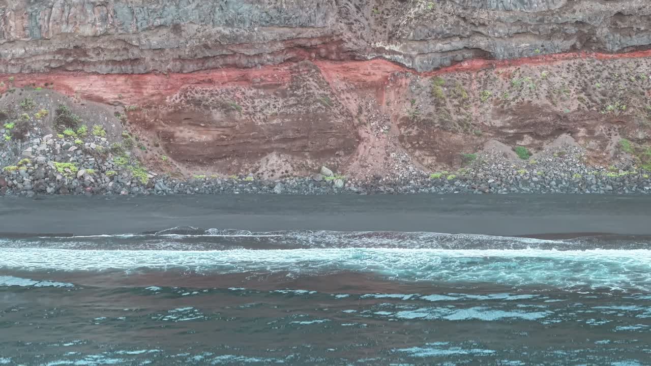 aerial view of blue ocean waves hitting black volcanic beach in Tenerife