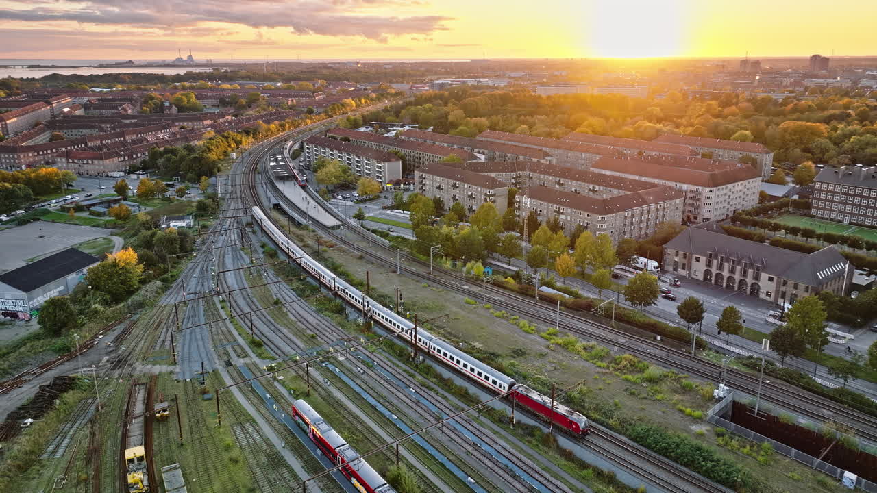 Aerial drone view of a train moving on the tracks near Vesterbro district in Copenhagen, Denmark at sunset