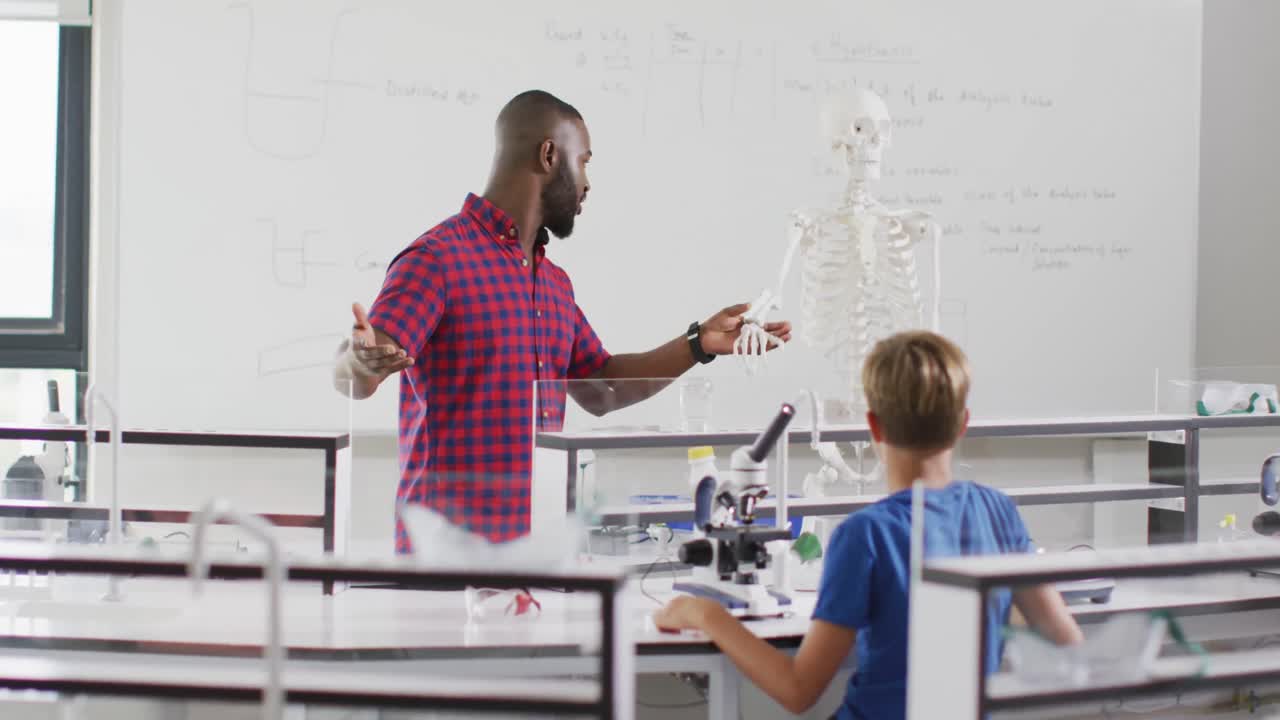 Video of happy african american teacher with class of diverse pupils during anatomy lesson