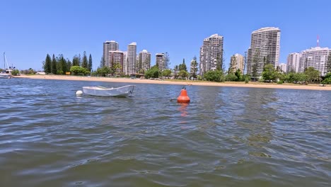 boat approaches buoy near gold coast cityscape
