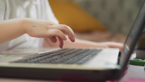 Kleiner-Junge-Tippt-Nachricht-Auf-Dem-Laptop,-Der-Am-Schreibtisch-Sitzt