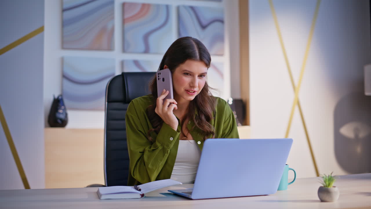 Donna al telefono mentre usa un portatile in ufficio