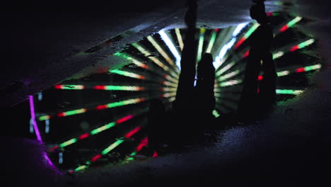 mirroring of ferris wheel in puddle. unknown people running on water in city.