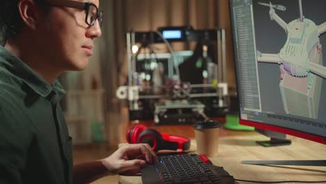 asian engineer working on personal computer and 3d printer, screen shows cad software with 3d prototype of drone delivery