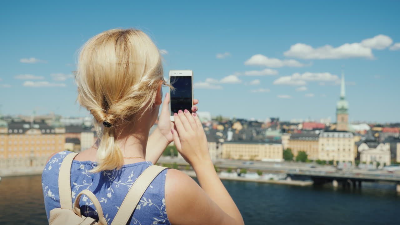 una mujer está fotografiando una hermosa vista de la ciudad de estocolmo en suecia vista trasera turismo en sc