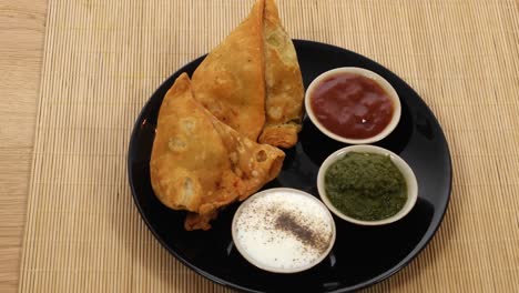 tilt down to a plate of samosa served with chutney