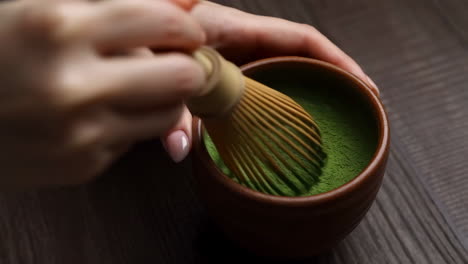 preparing matcha tea with a bamboo whisk