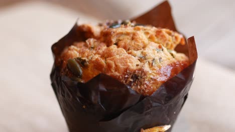 close up of a single pumpkin seed muffin in a brown paper liner