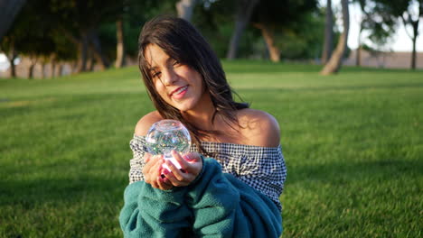 Una-Linda-Joven-Hispana-Sonriendo-Alegremente-En-Un-Parque-Con-Una-Bola-De-Cristal-Mágica