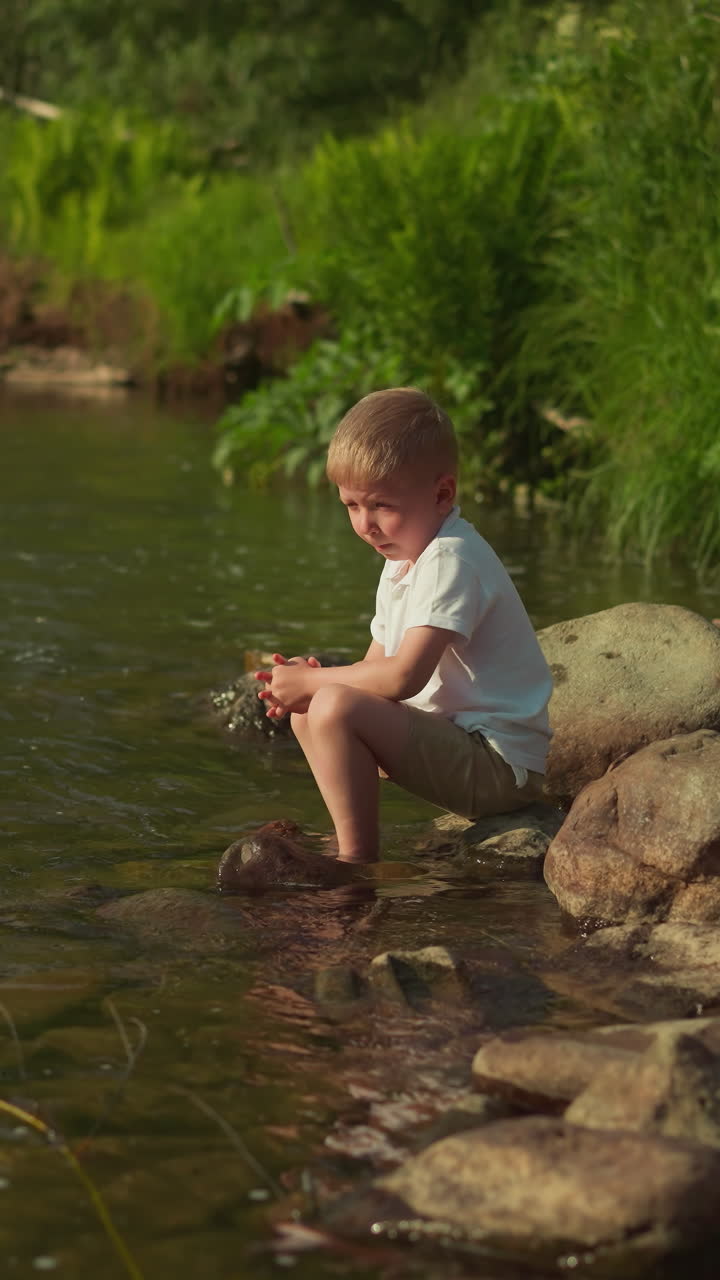 작은 소년은 은 날 강변에 휴식을 취하고 있는 자갈로 놀고, 사려 깊은 아이는 큰 바위 위에 앉아서 여름 휴가를 생각하고 있다.
