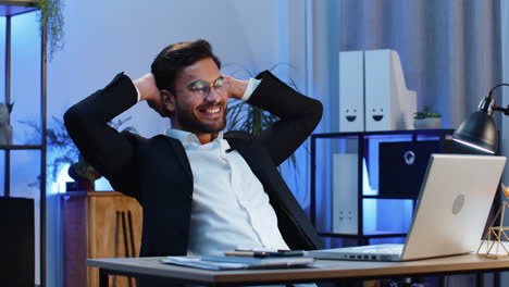 indian businessman freelancer taking break leaning on chair after working celebrating success