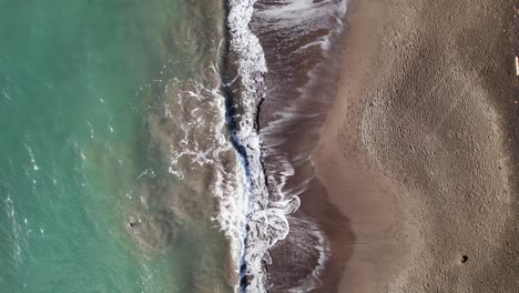 beautiful waves flow over sandy beach of guadeloupe, aerial top down view