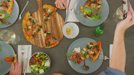 vista aérea de amigos en un restaurante de pizza comiendo comida y tomando selfies en el teléfono móvil