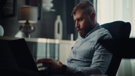 professional financial expert working on trading strategy using laptop, monitoring real-time stocks and exchange market charts, making investments. successful businessman in comfortable home office.