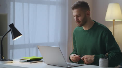 Mann-Setzt-Während-Der-Arbeit-Mit-Dem-Laptop-Eine-Brille-Auf,-Um-Seine-Augen-Zu-Schützen,-Und-Arbeitet-Von-Zu-Hause-Aus-Am-Tisch-Im-Zimmer