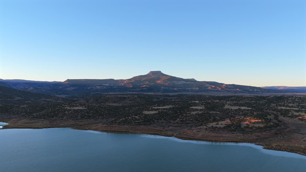 Spectacular view of a desert reservoir beneath a flat top peak. The landscape features Cerro Pedernal and Abiquiu Lake in New Mexico, famous for Georgia Okeeffe