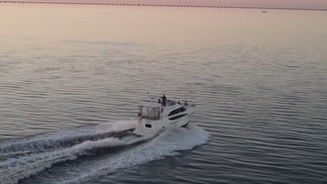 private motor yacht cruising and leaving wake on sea surface at sunset