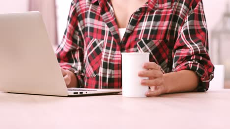 midsection of a woman using laptop while drinking coffee