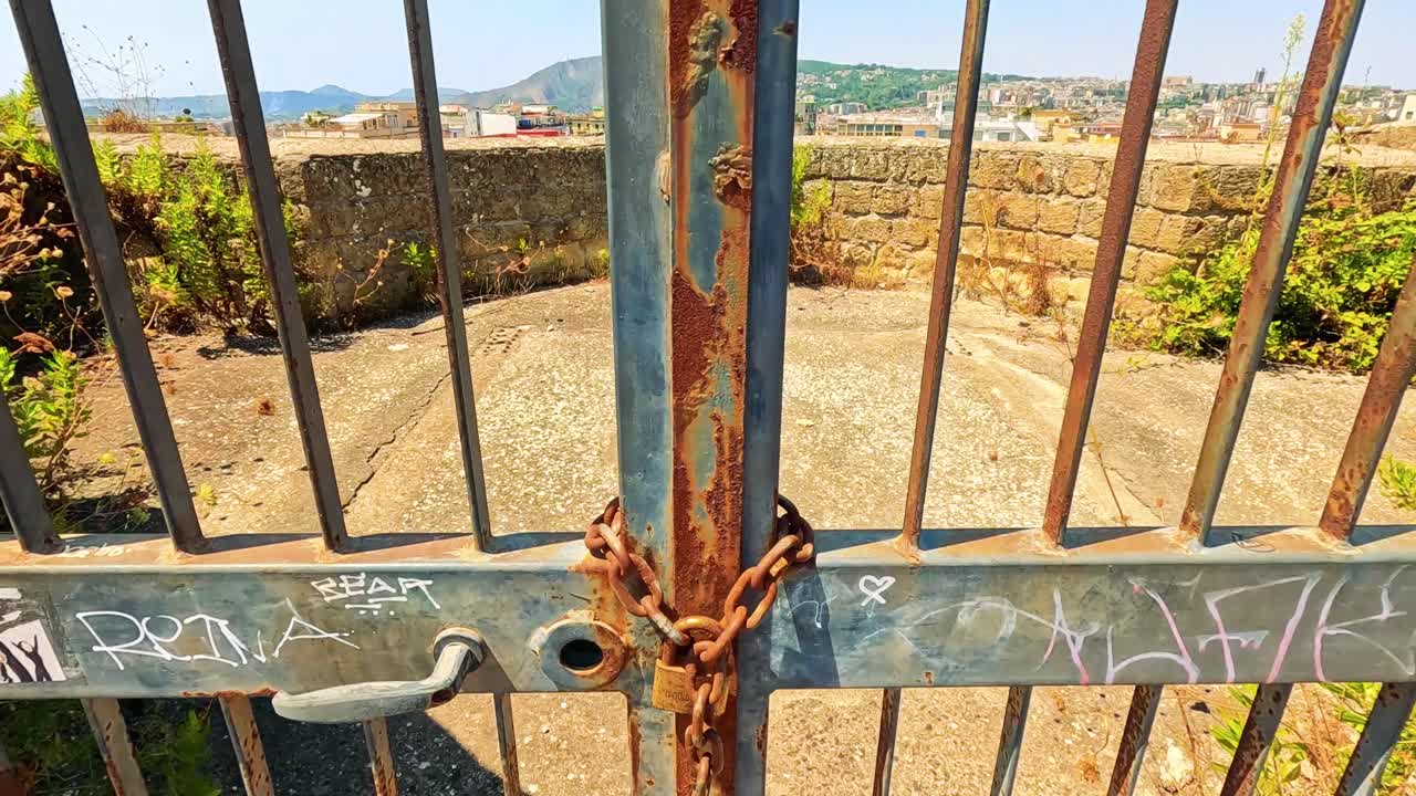 Cancello arrugginito incornicia una vista panoramica di Napoli