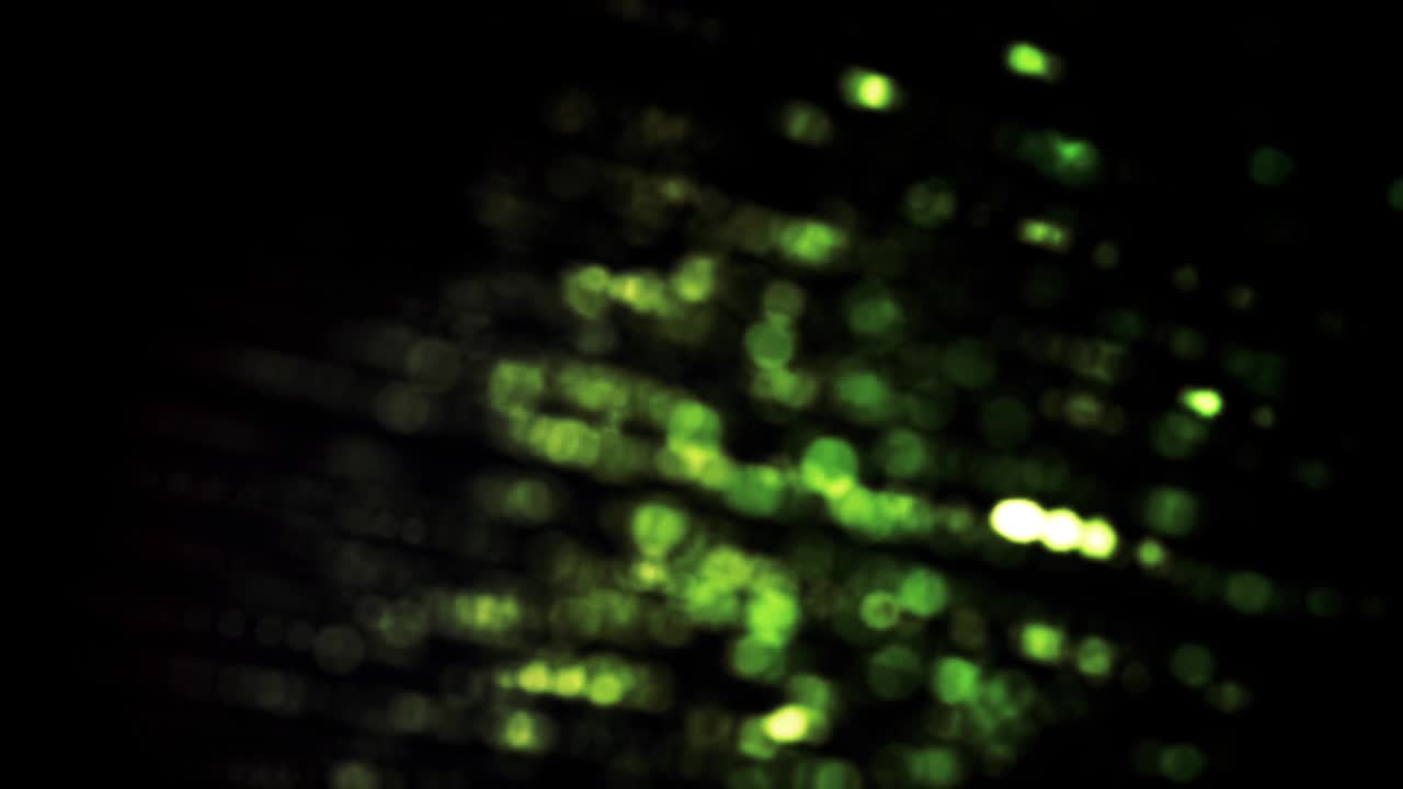 hileras coloridas de pequeños puntos que giran sobre un fondo negro, bucle sin costuras. animación. nube de bokeh verde girando y moviéndose