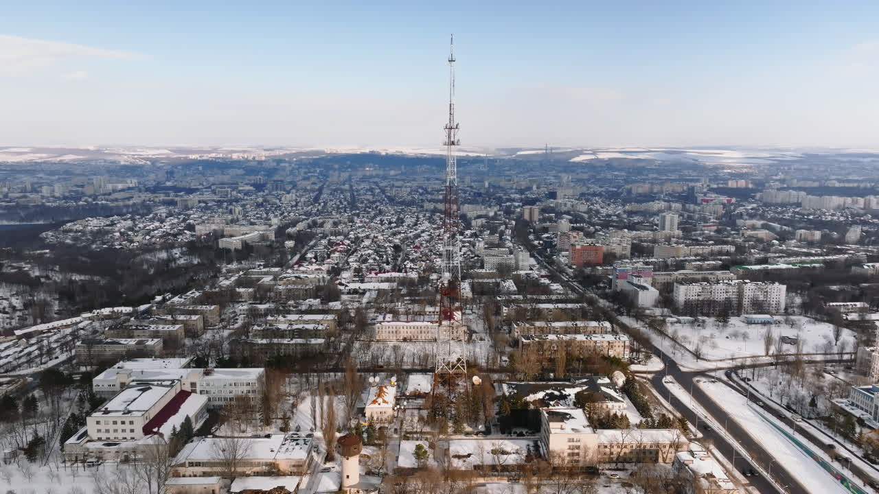 Aerial drone view of the radio transmission tower in the daylight. Ground covered in snow in Chisinau, Moldova