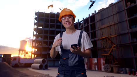 un trabajador asiático señala un teléfono inteligente en su mano en un sitio de construcción