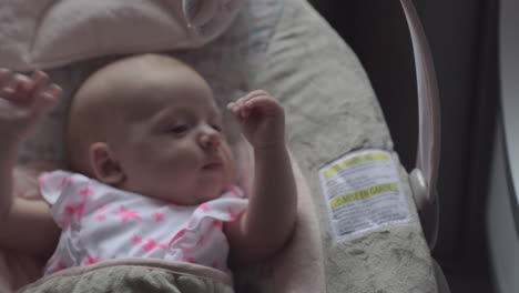 Baby-girl-looking-at-washing-machine-lying-in-bouncy-seat