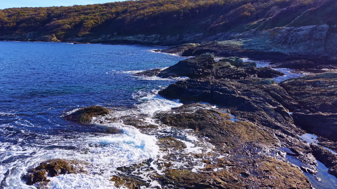 Waves crash against rocky shorelines at sunset, revealing nature's splendor along the coast near tranquil waters