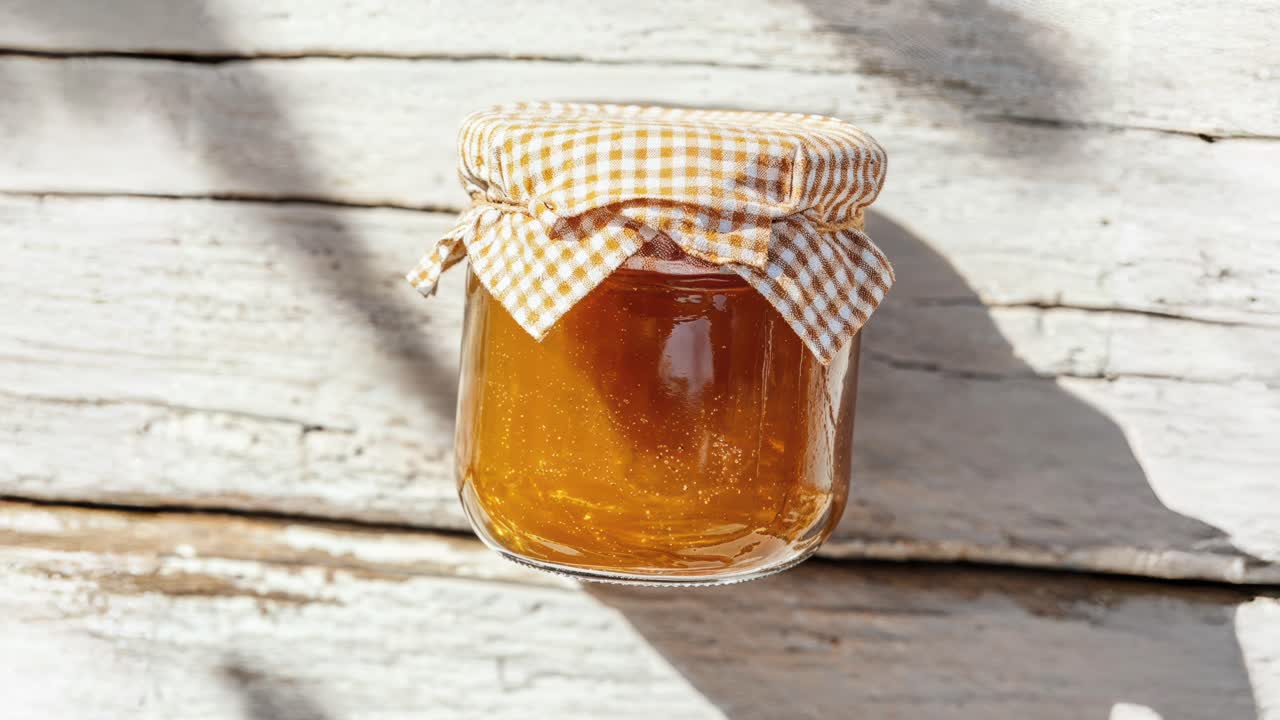 Glass Jar of Honey with Gingham Cloth on Rustic Wood