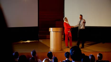 gente de negocios multiétnica estrechando la mano en el escenario en el seminario de negocios en el auditorio 4k