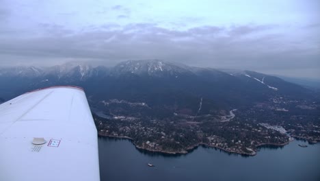 pilot view of airplane's wing in flight and mountain coastal landscape