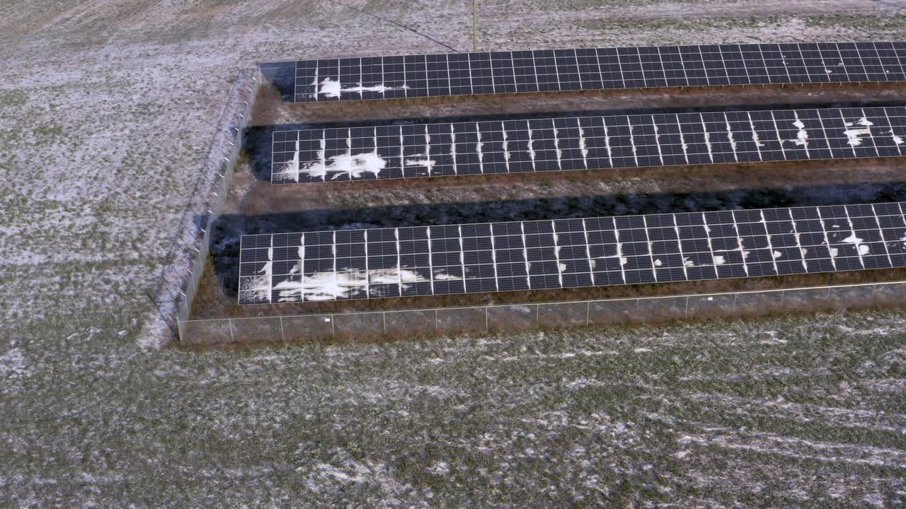 vista aérea de drones de una estación de paneles solares ligeramente cubierta de nieve que alimenta una granja