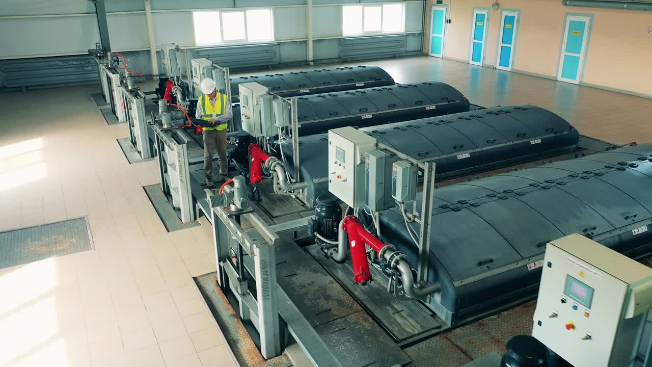 vista dall'alto di un operaio maschio che regola i serbatoi di acque reflue al chiuso