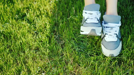 female legs in white sneakers on a green lawn 4k slow motion video