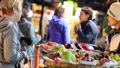 foreigners buying fruit from a street vendor