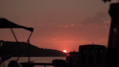 time lapse of sunset with swaying boats, sea and island in the foreground