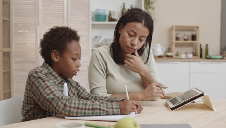 mother helping son with homework at home